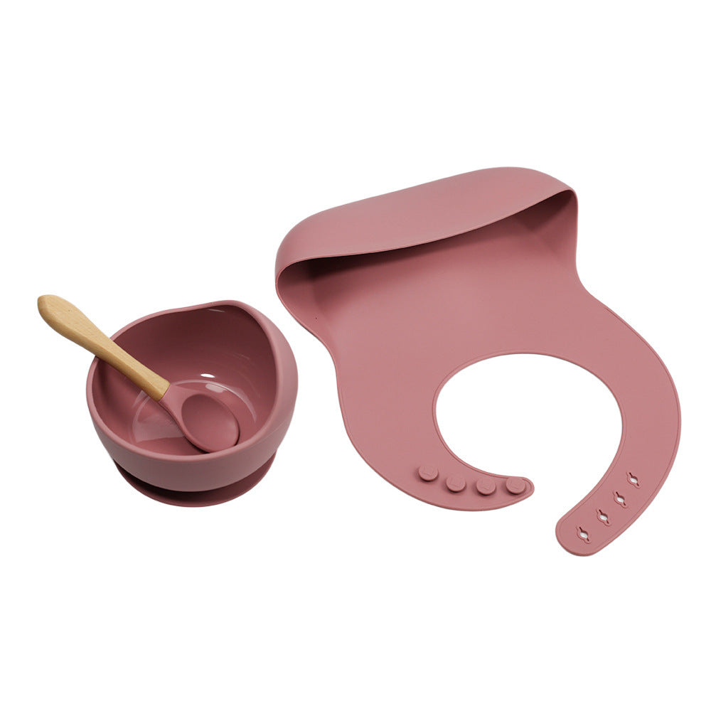Pink baby bowl, spoon, and bib set on a white background