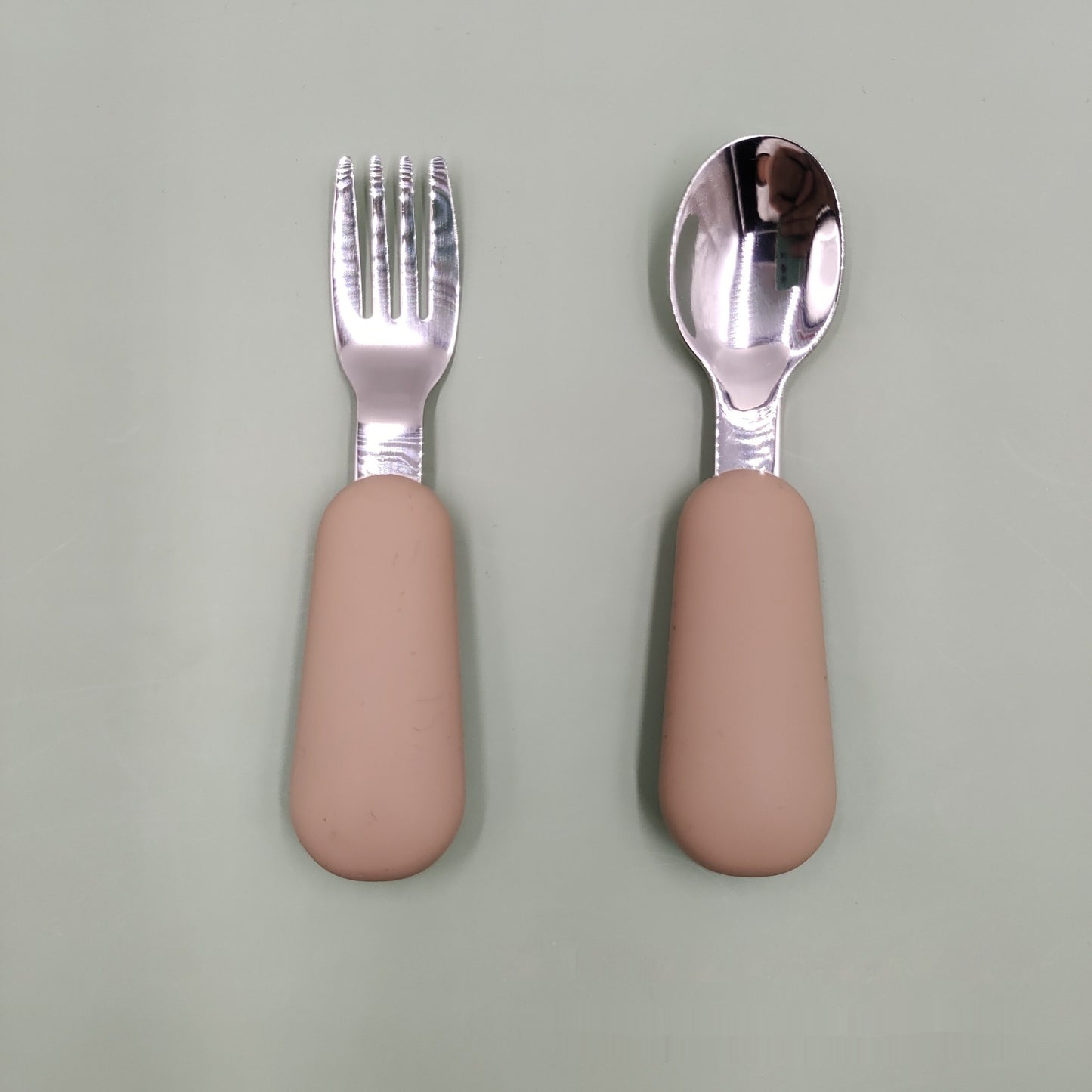 Fork and spoon set with pink handles on a light gray background