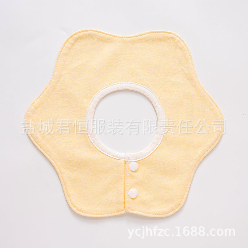 Yellow baby bib with white buttons on a light gray background