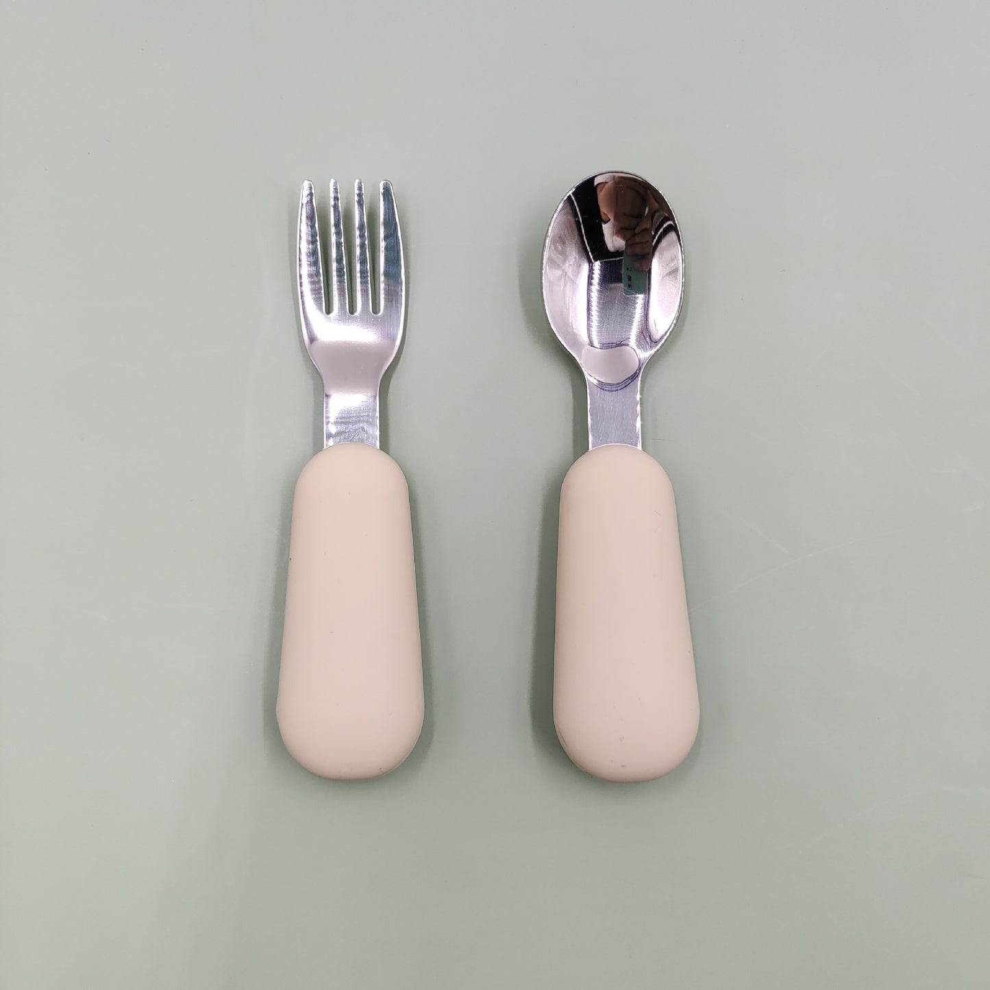 Set of fork and spoon with beige handles on a light gray background