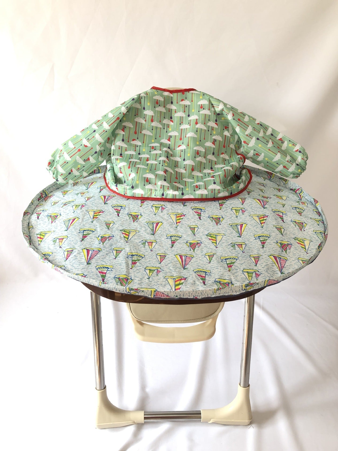 Baby bouncer with green and red patterned cover on a white background