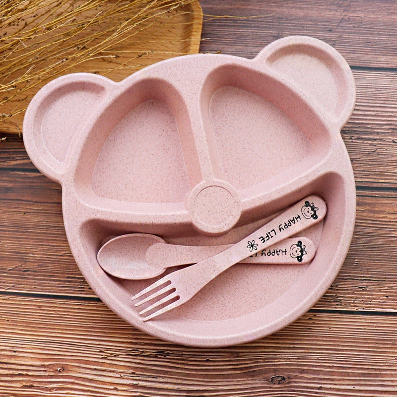 Pink bear-shaped plate with spoon, fork, and 'Happy Life' branding on a wooden surface