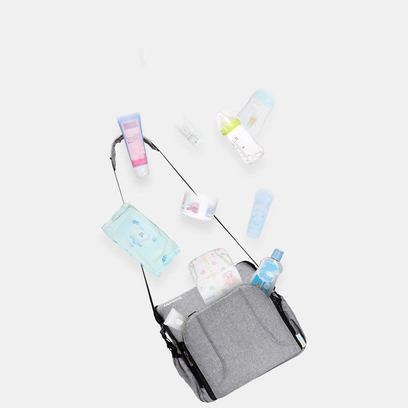 Gray diaper bag with baby products on a white background