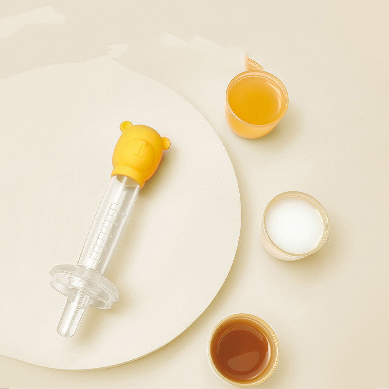 Yellow baby bottle with a round white plate on a beige background
