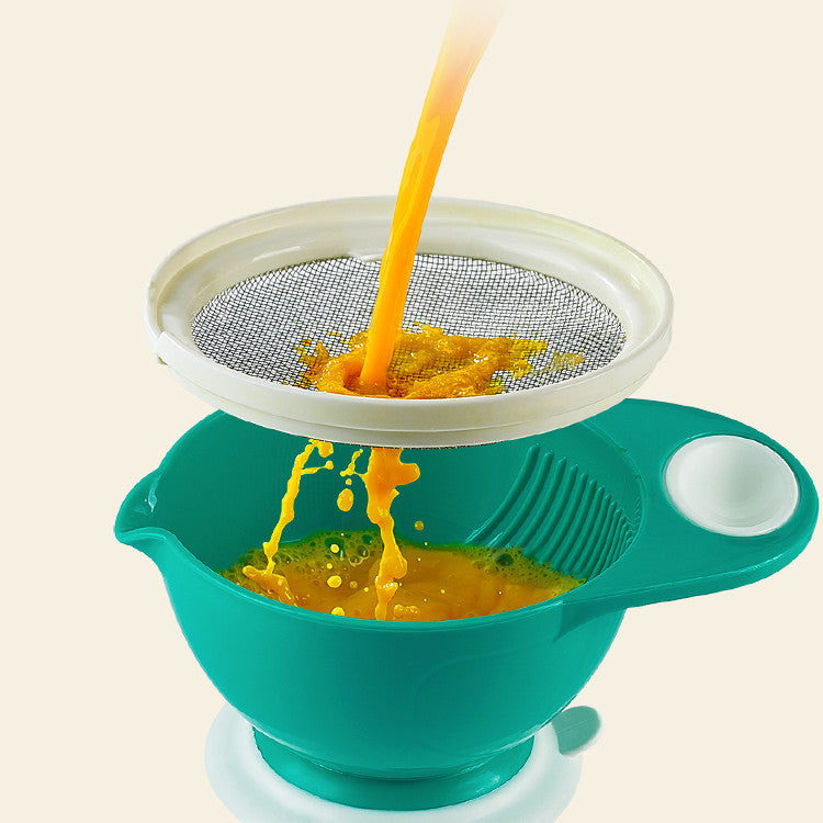Green colander with a white rim being used to strain orange juice.