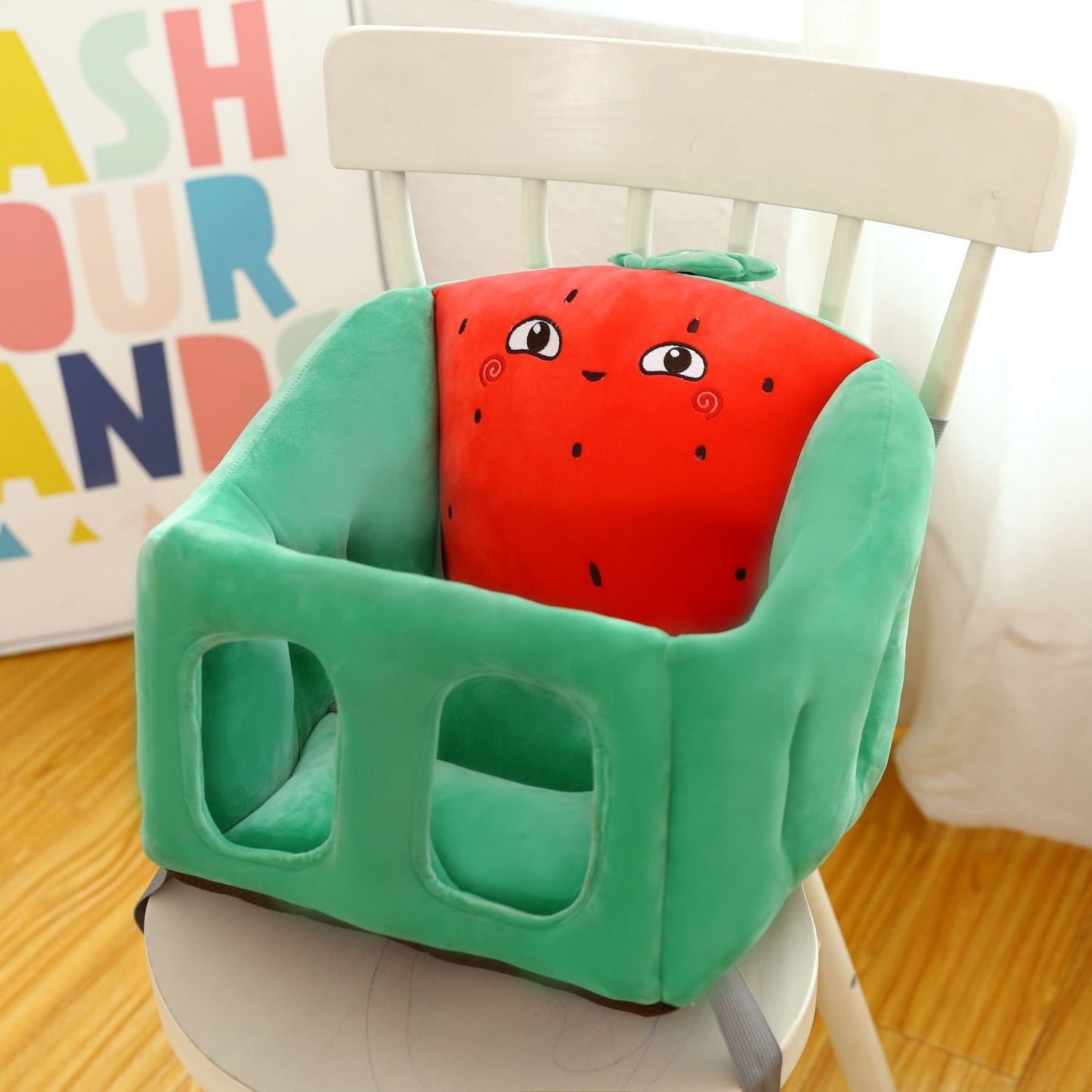 Children's high chair with a cartoon watermelon design on a wooden floor.