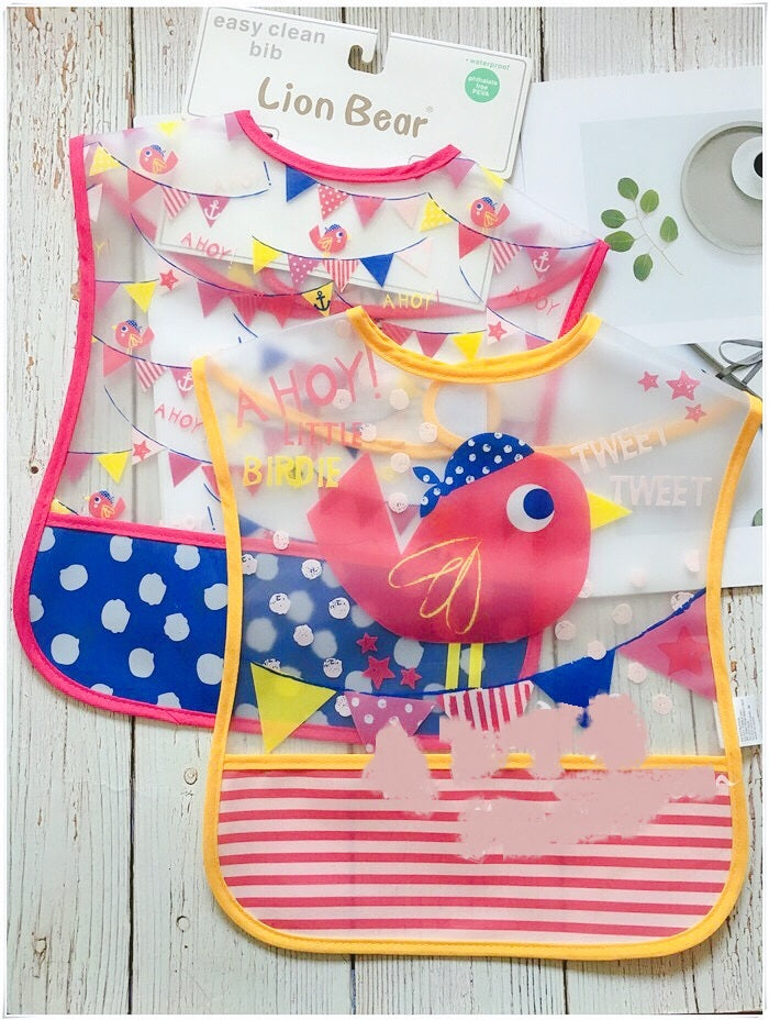Colorful baby bibs with cartoon designs on a wooden surface