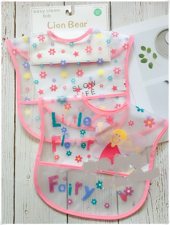 Baby bib with colorful designs and text on a wooden surface