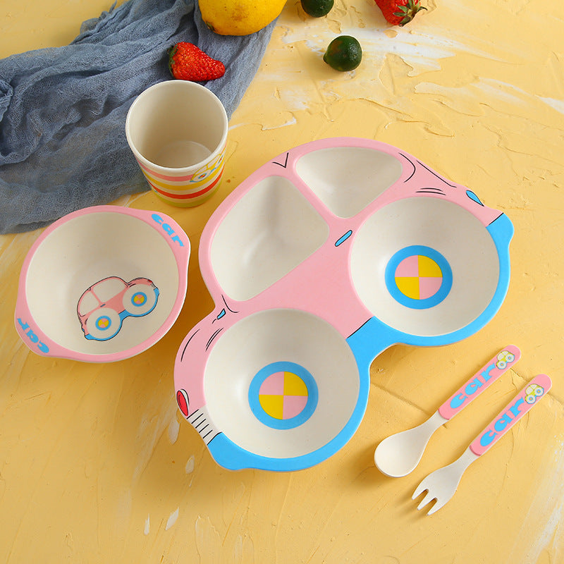 Children's tableware set with divided plate, bowls, spoon, and fork on a yellow surface.