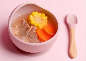 Bowl of soup with vegetables on a pink background