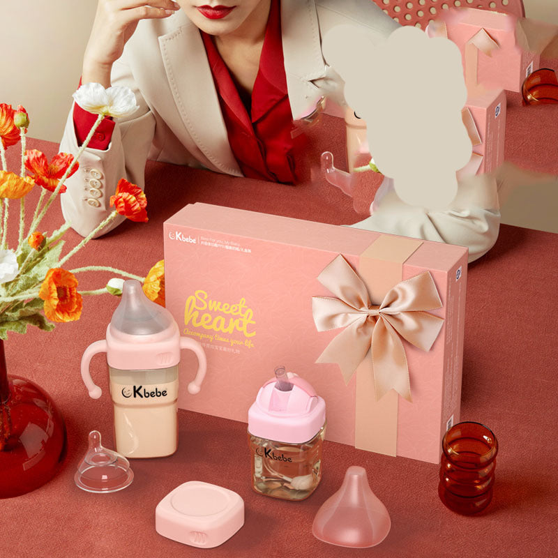 Kibebe baby bottle set with pink box and decorative elements on a table.