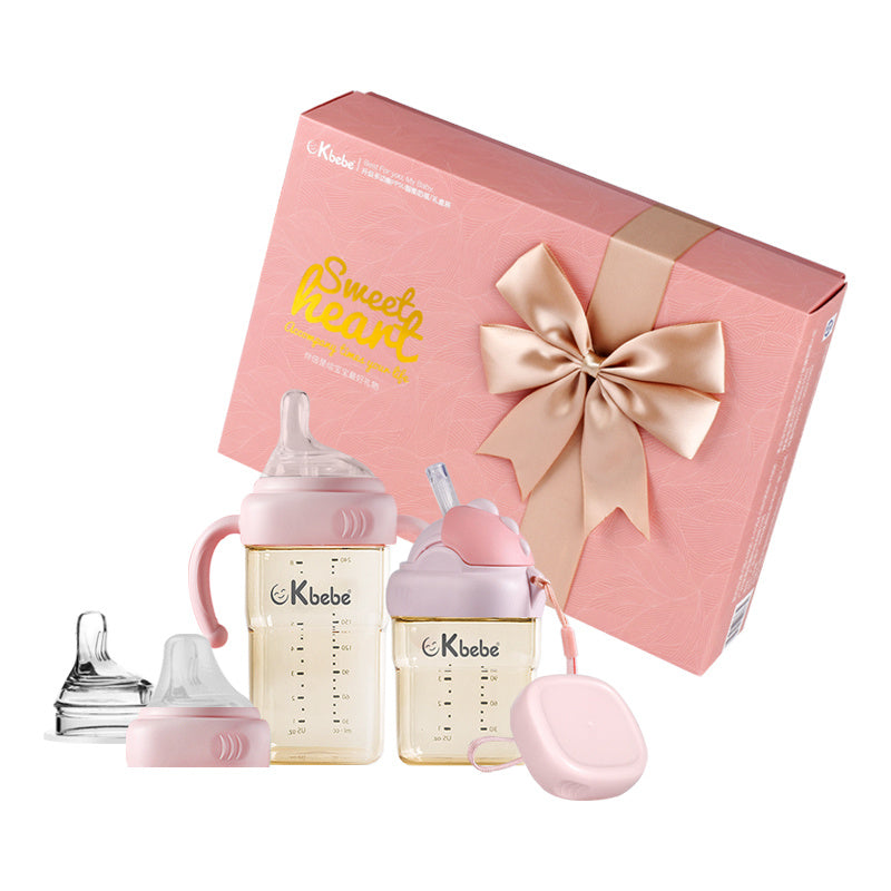 Baby bottle set with Kbebe branding in front of a pink gift box with a bow.