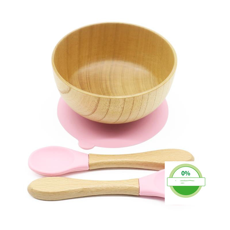 Wooden bowl with pink suction cup and spoons on a white background