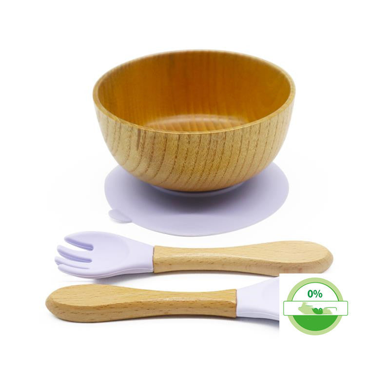 Wooden bowl with silicone suction cup, purple spoon, and white fork on a white background