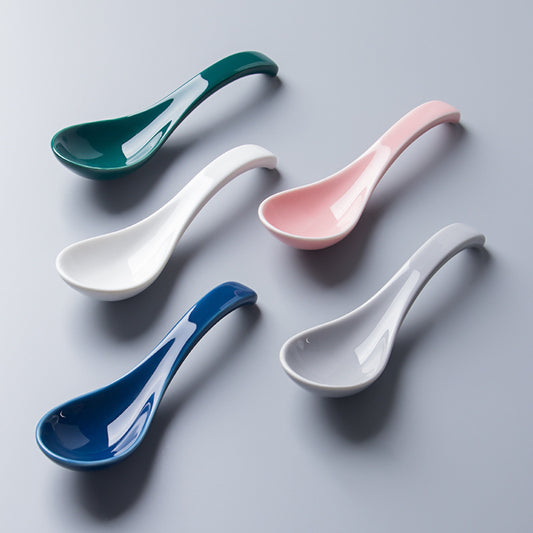 Five ceramic spoons in different colors on a gray background