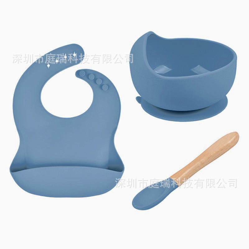 Blue baby bib, bowl, and wooden spoon set on a white background