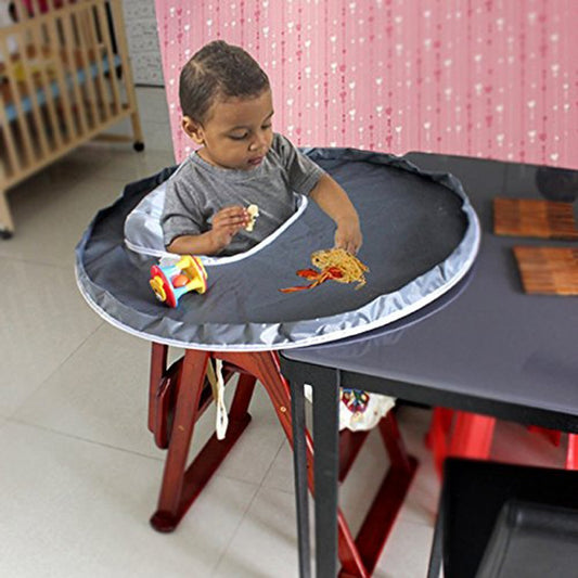 Child sitting at a table with a portable dining setup, eating noodles.