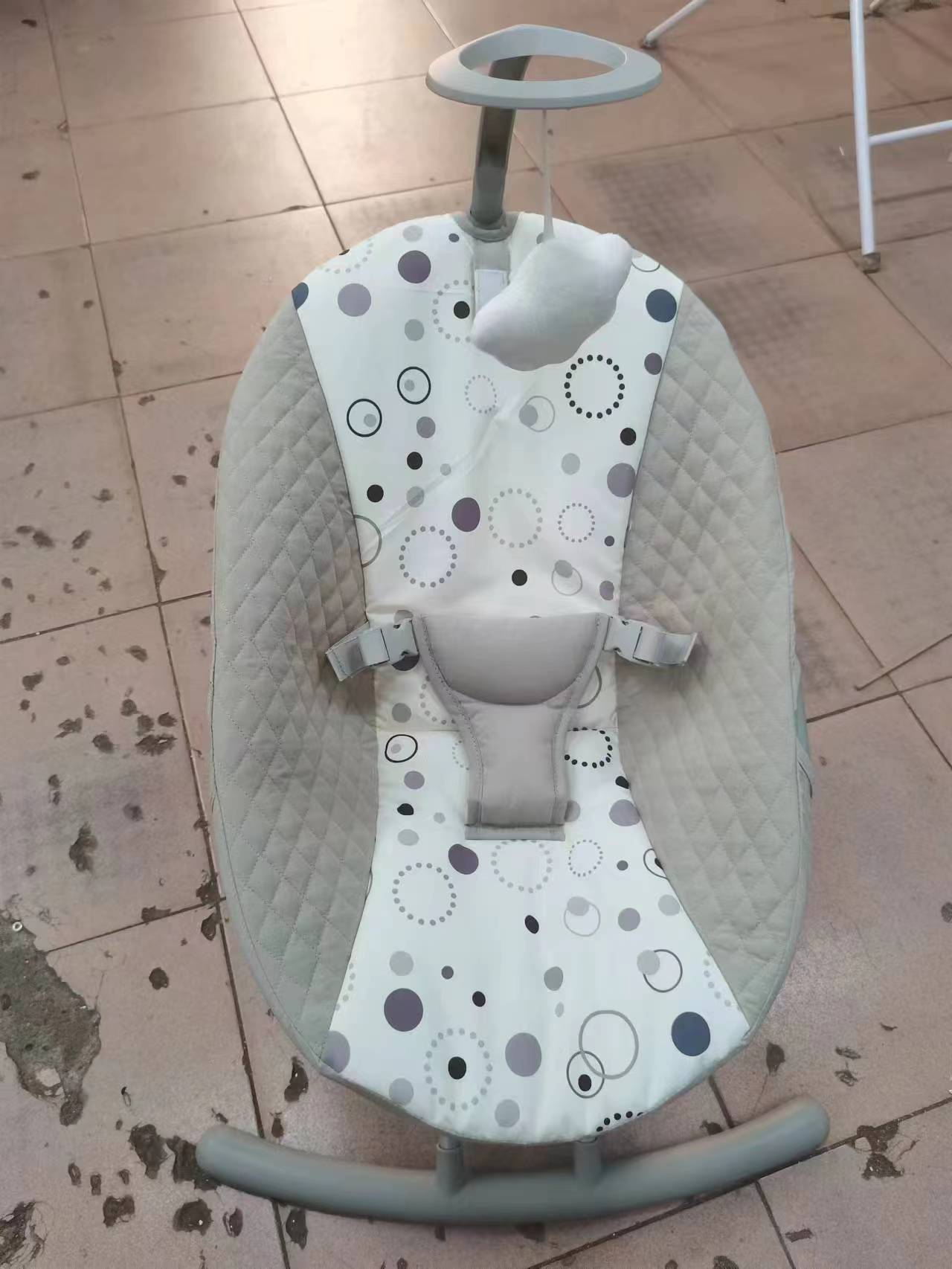 Baby swing with polka dot design on a tiled floor