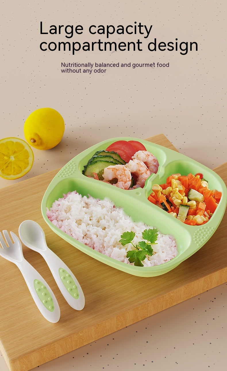 Green compartmentalized plate with food on a wooden board, lemon slices on the side.