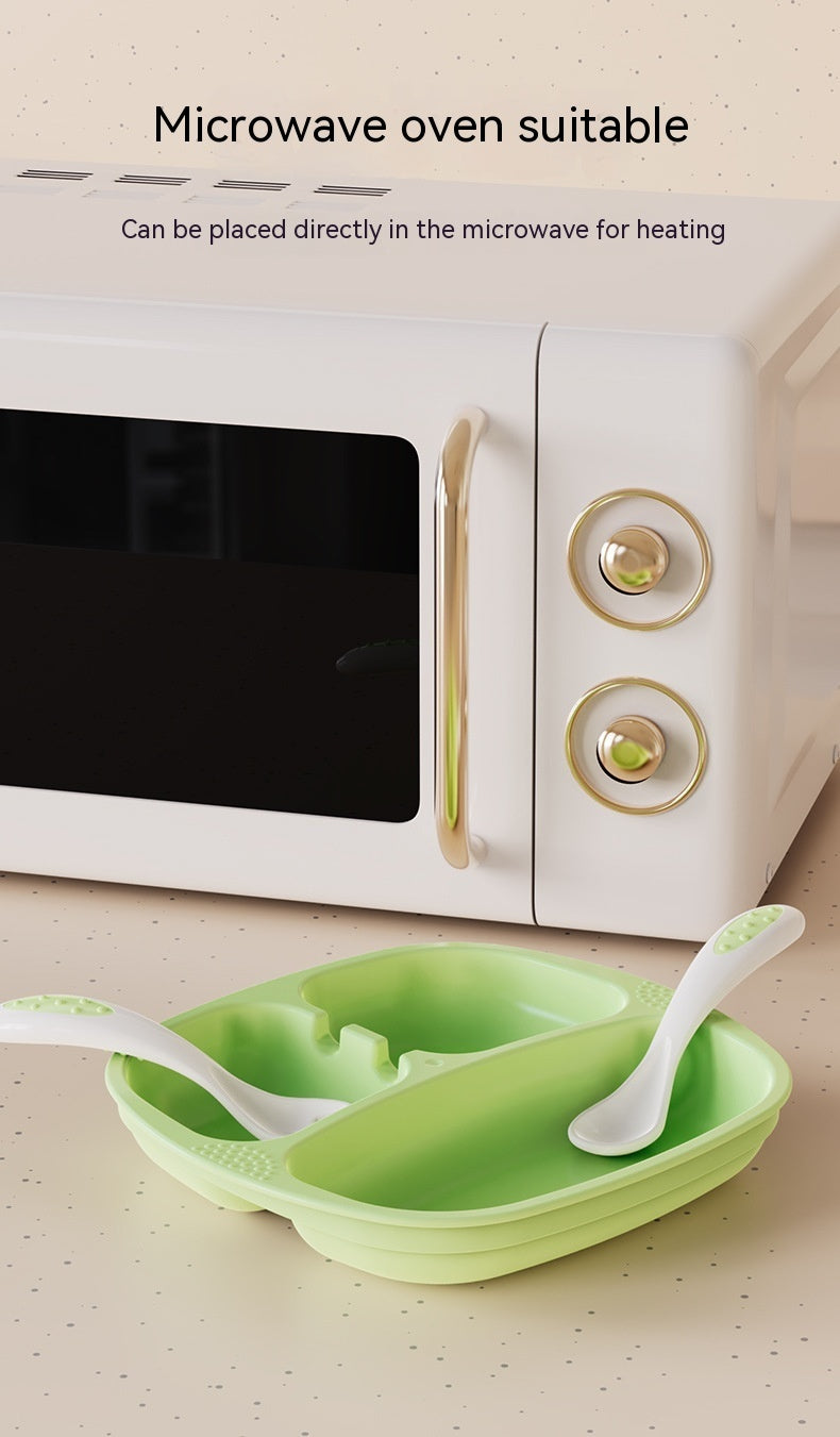 Green silicone food steamer with two white spoons on a beige surface, with a microwave in the background.