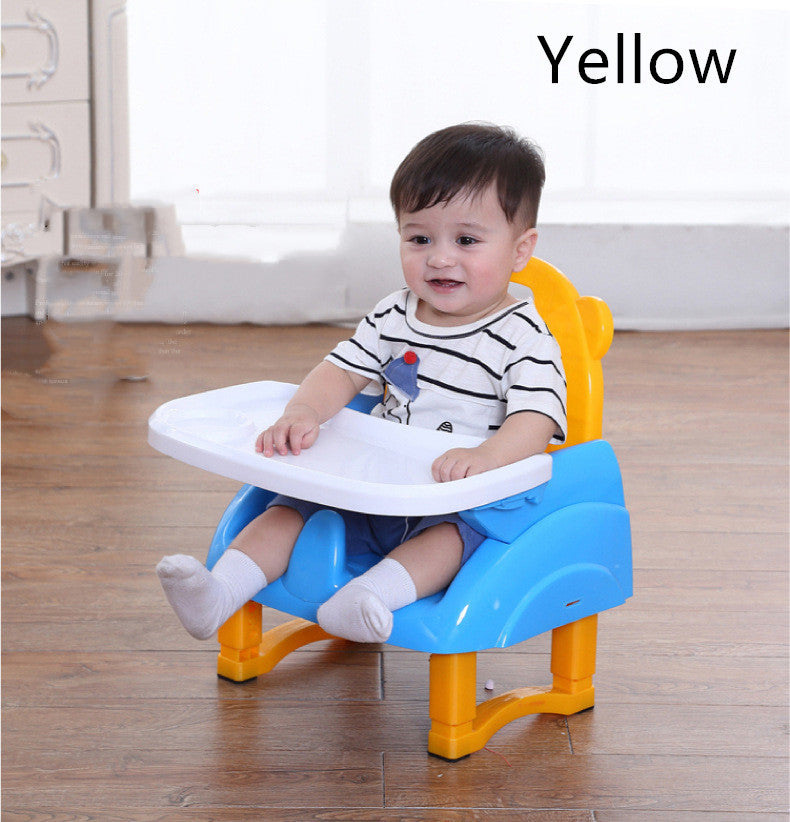 Child sitting on a yellow and blue booster seat with a white tray.