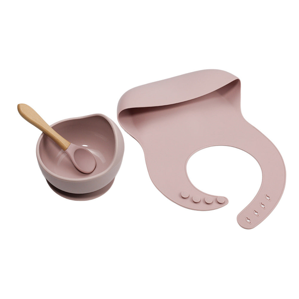 Pink baby bowl, spoon, and bib set on a white background