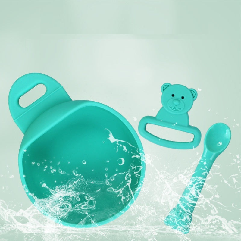 Set of turquoise baby utensils including a bowl, spoon, and teether on a light green background.