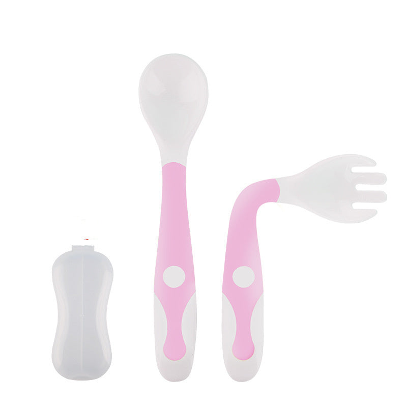 Set of pink and white baby utensils including a spoon, fork, and straw on a white background