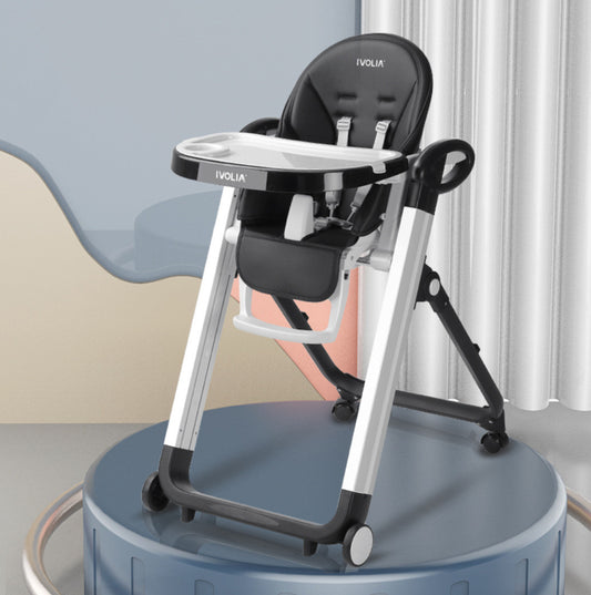 Black and silver baby high chair on a blue platform with a light blue wall and white curtain in the background.
