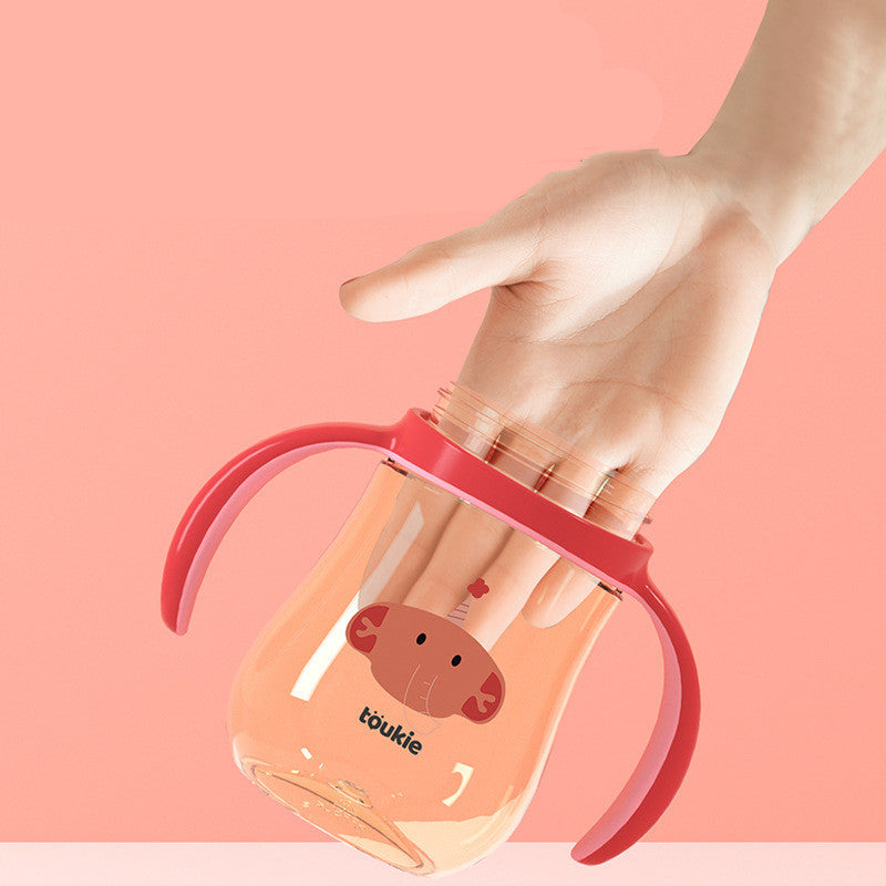 Hand holding a pink and clear tumbler with a cartoon character on a pink background
