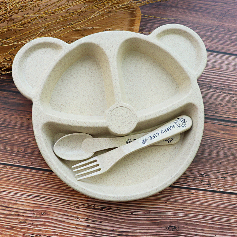 Children's plate with bear design, spoon, fork, and cup on a wooden surface