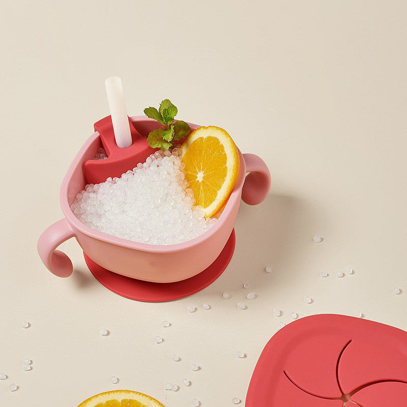 Pink children's cup with straw, lid, and ice cubes on a beige background