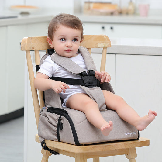 Child sitting in a high chair with a baby seat booster in a kitchen setting