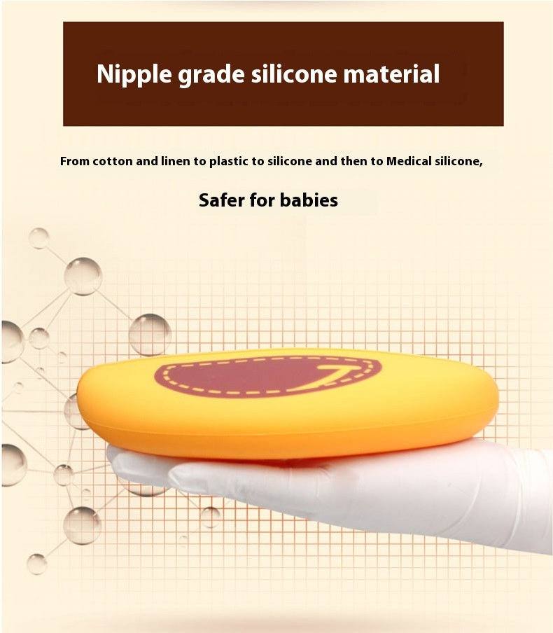 Yellow object with a purple center held by a gloved hand, text about nipple grade silicone material on a beige background.