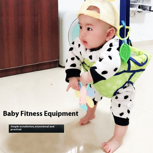 Baby wearing a green and black polka dot outfit with a bib, standing on a tiled floor.