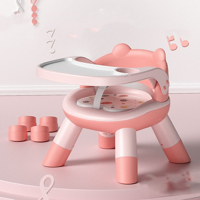 Pink and white children's chair with a small table on a light pink floor.
