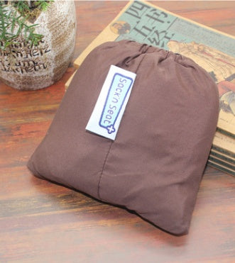 Brown drawstring bag with a label on a wooden surface