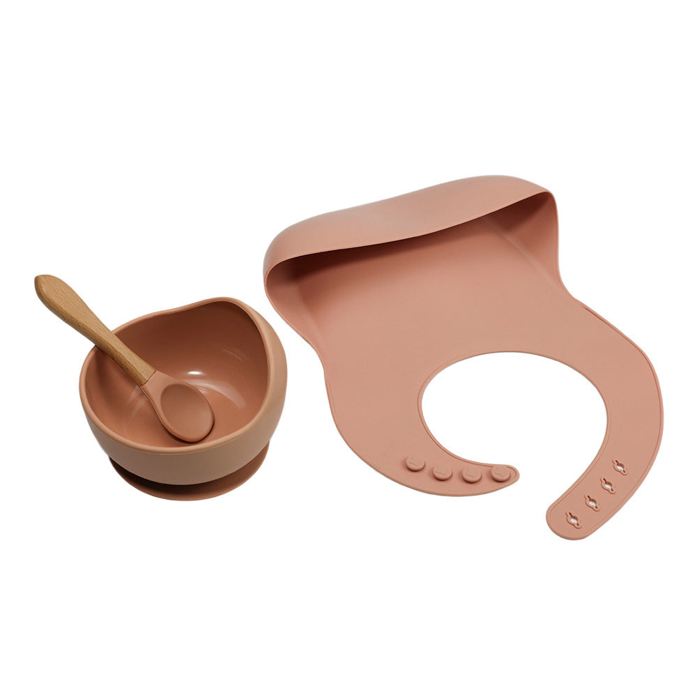 Pink baby bowl, spoon, and bib set on a white background