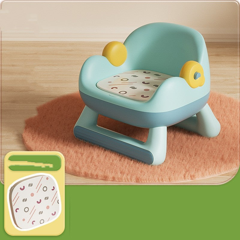 Children's chair with a patterned cushion on a wooden floor, accompanied by a small book with a similar design.