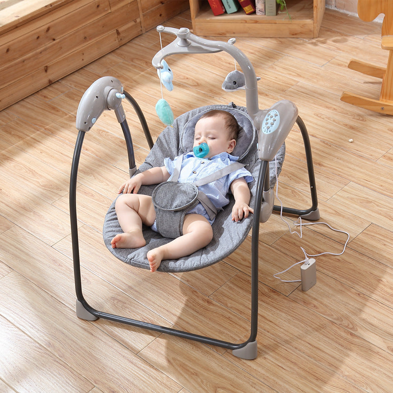Baby in a gray baby swing on a wooden floor