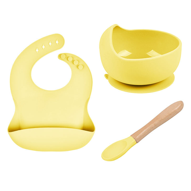 Yellow baby bib, bowl, and spoon set on a white background