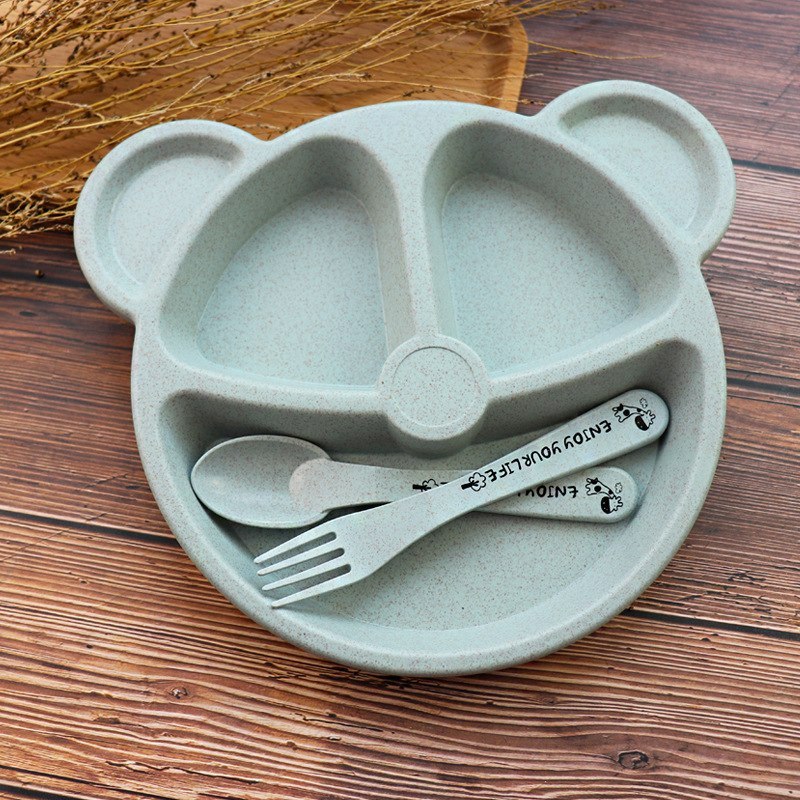 Children's plate with bear design, spoon, and fork on a wooden surface