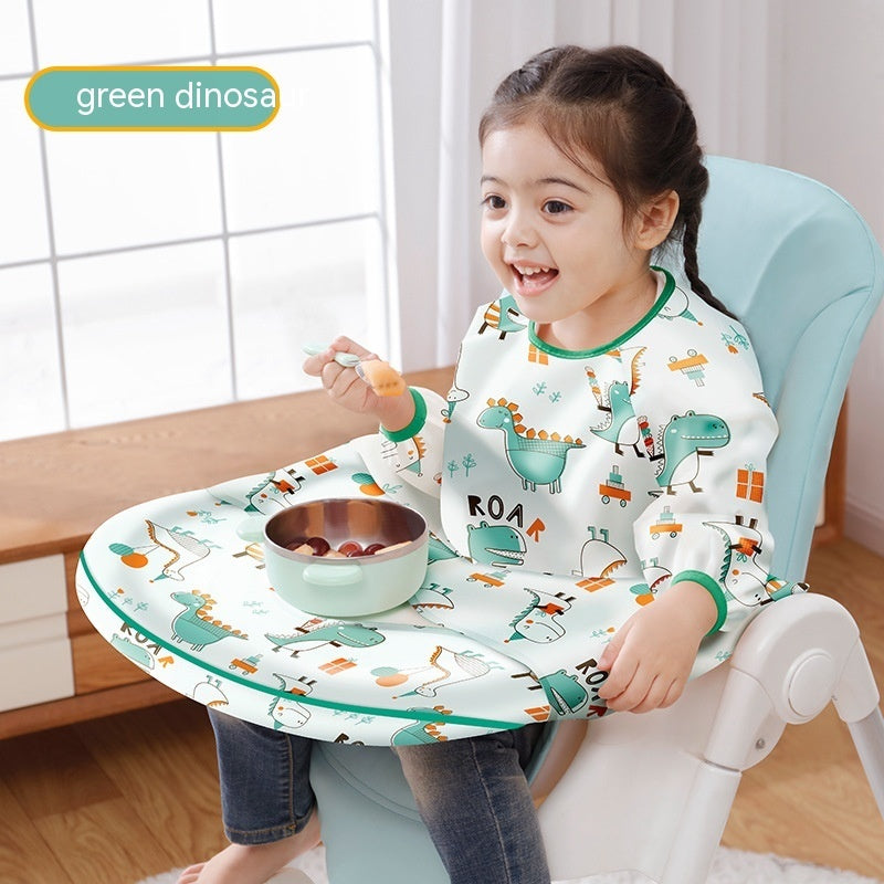 Child sitting in a high chair with a dinosaur-themed seat pad and bib, smiling.