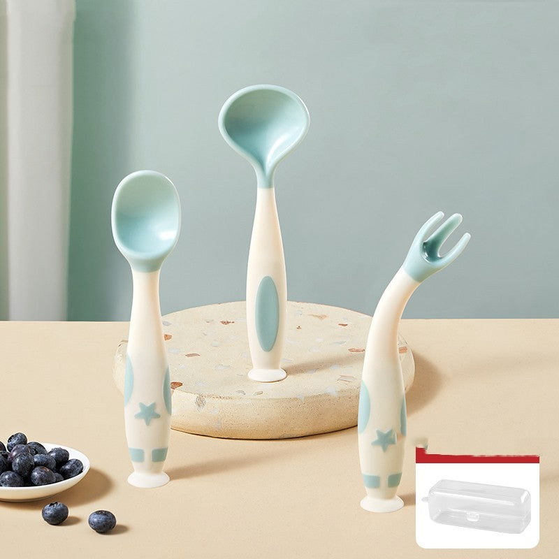 Set of baby utensils including spoons and a fork on a wooden surface with berries and a container.