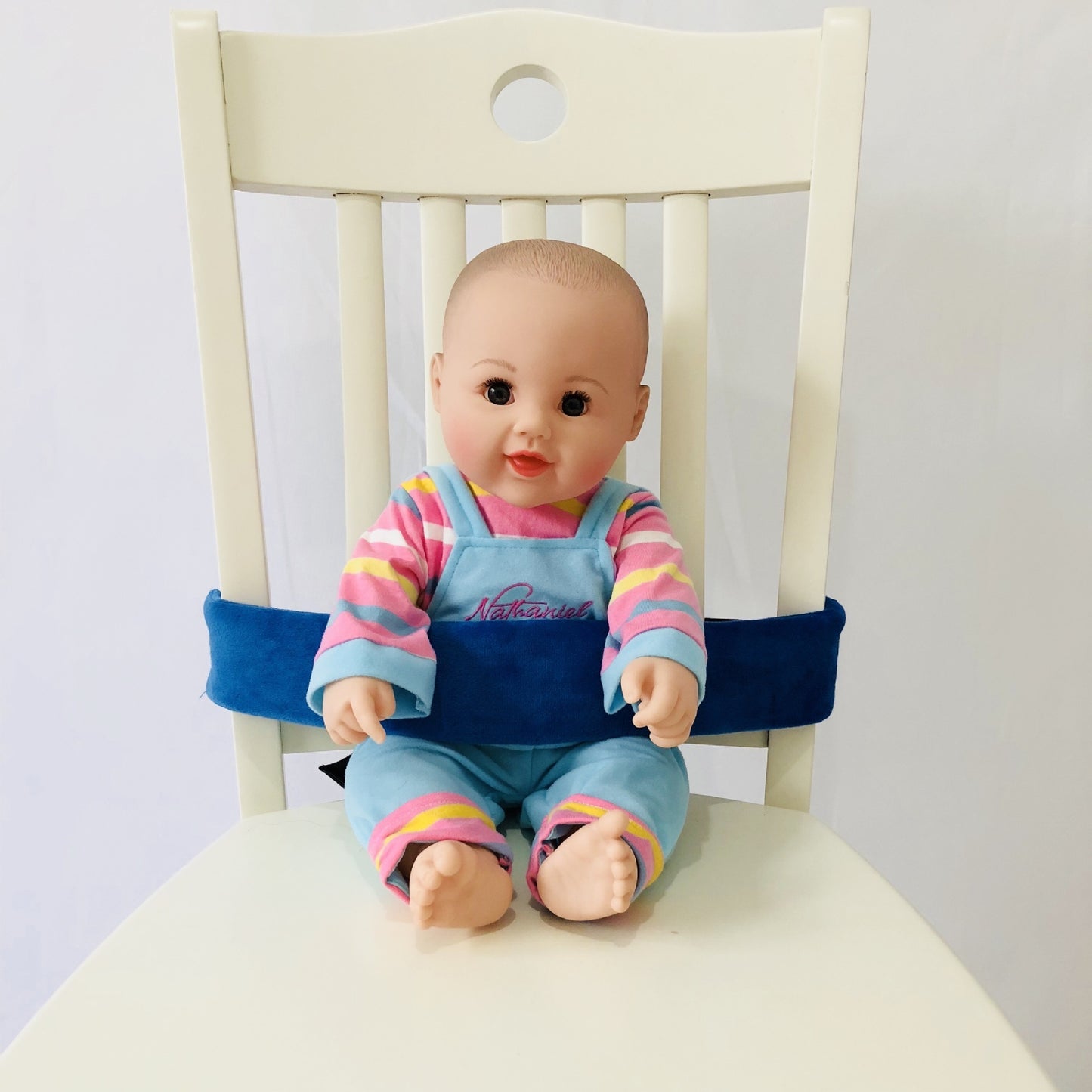 Baby doll sitting on a chair with a blue cushion