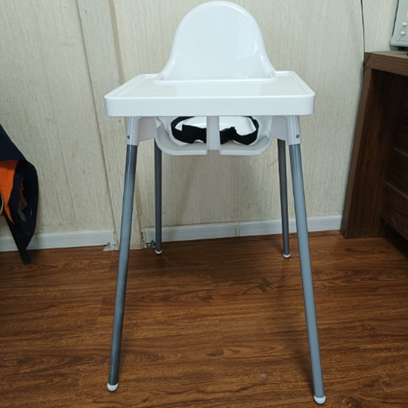 White high chair with gray legs on a wooden floor against a beige wall.