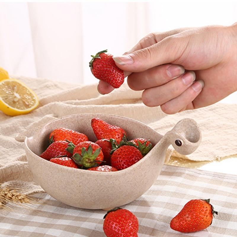 Hand picking a strawberry from a decorative bowl filled with strawberries on a tablecloth.