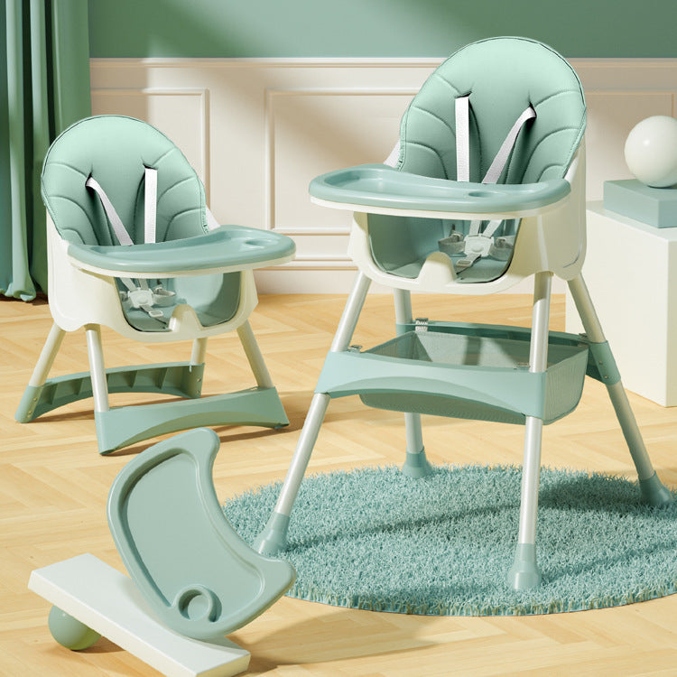 Green baby high chair with tray and base on a wooden floor.