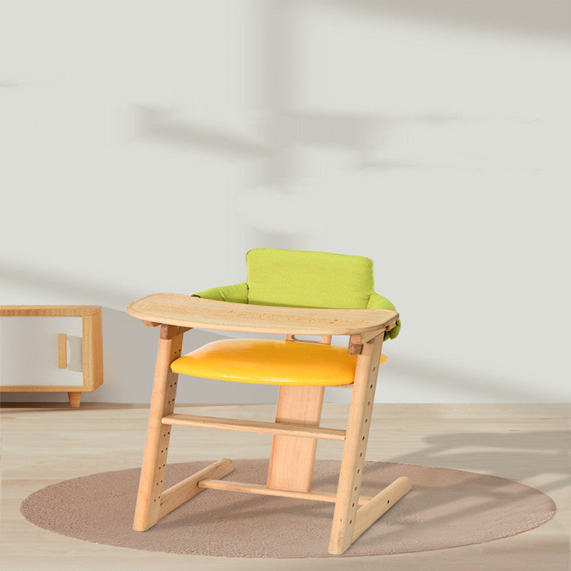 Children's high chair with green cushion and orange seat on a light wooden frame, placed on a beige rug.