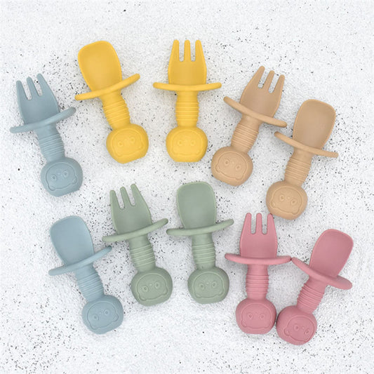 Set of colorful silicone utensil-shaped teethers on a textured white background